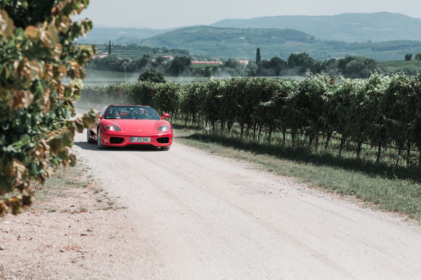 Roter Ferrari faehrt durch die Weinberge beim Senti Vini Sommerfest 2017 nahe Verona