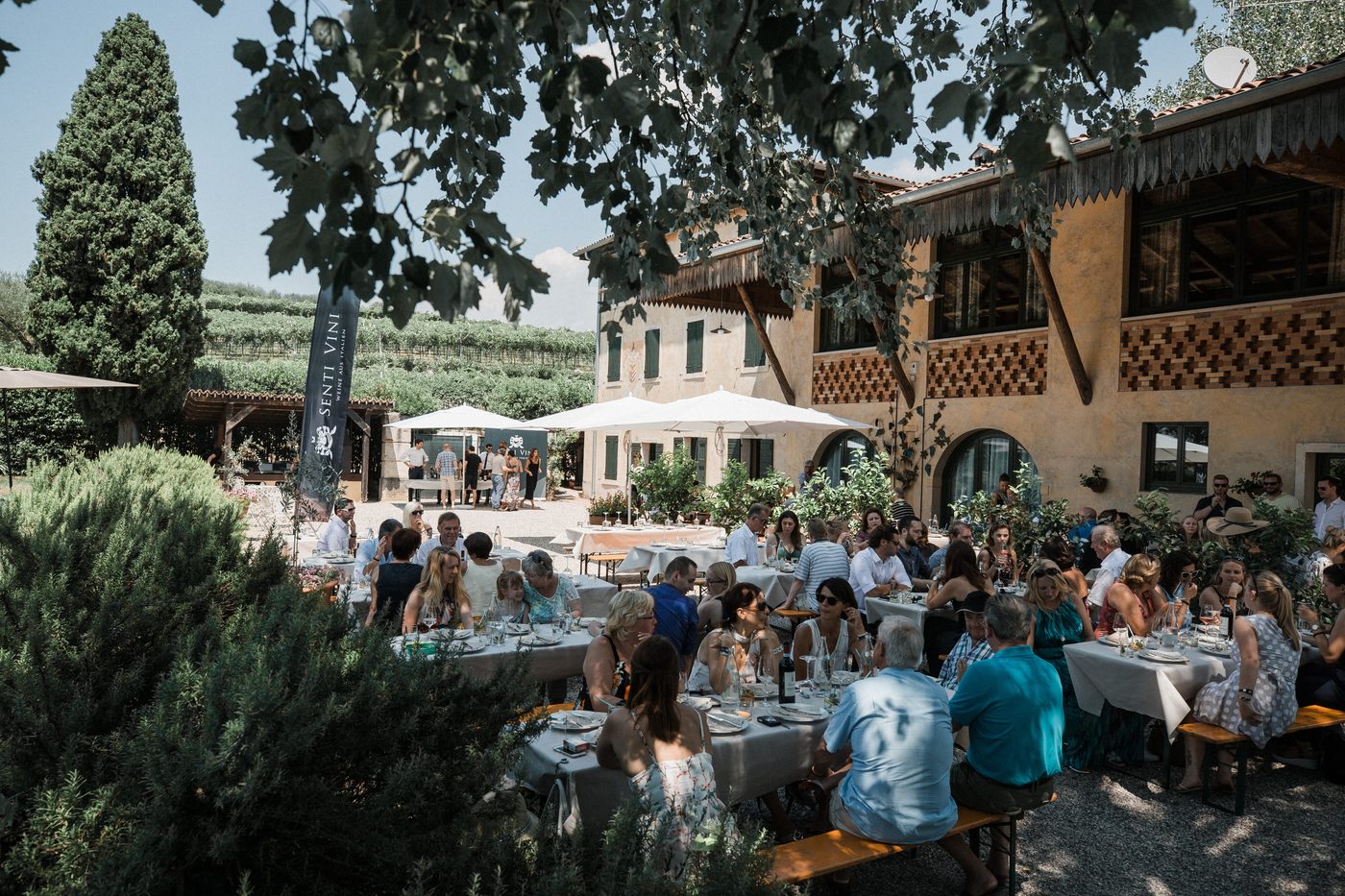 Gaeste beim Mittagessen im Garten des Weinguts beim Senti Vini Sommerfest 2017 in Verona