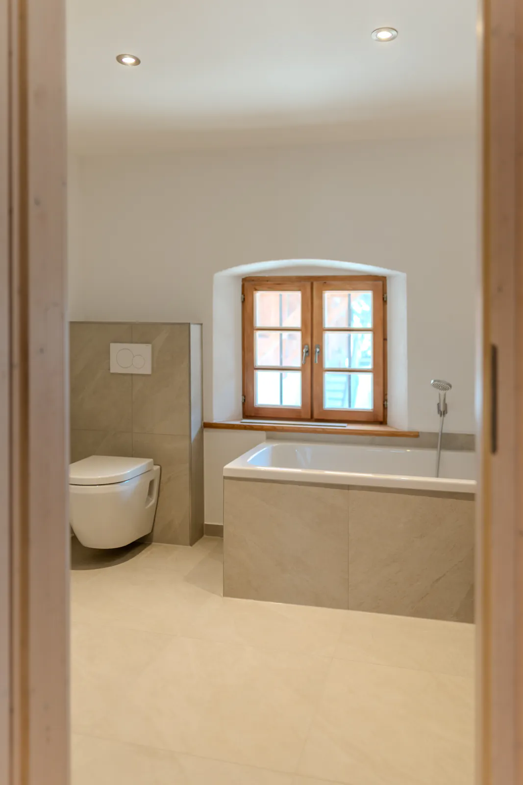 Badezimmer mit Badewanne und Holzfenster im renovierten Altbau