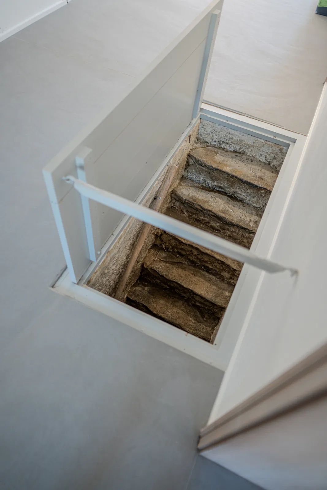 Historische Natursteintreppe unter einer geöffneten Bodenluke