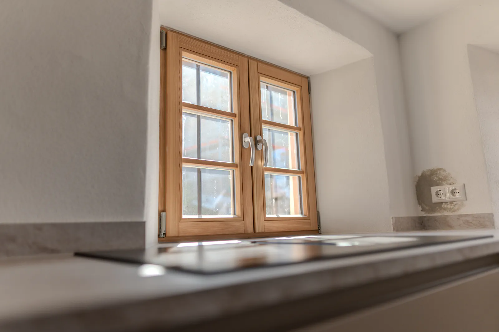 Arbeitsplatte der Küche vor einem Holzfenster in tiefer Laibung