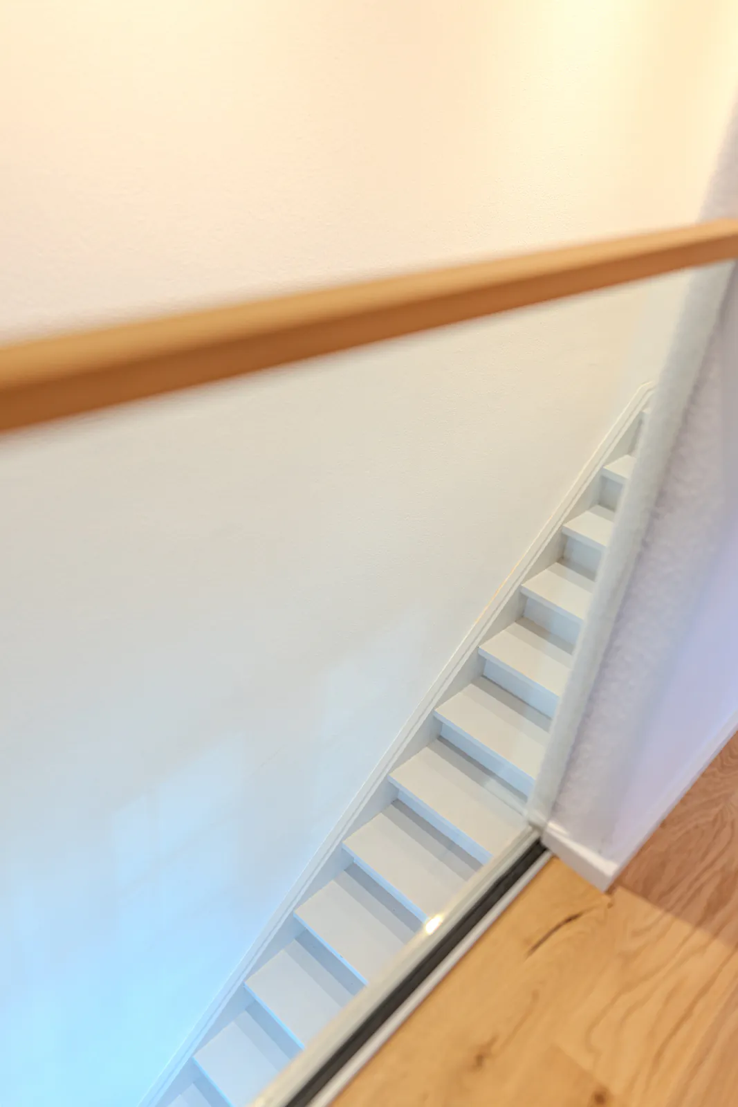 Weiße Treppe mit Handlauf aus Holz im renovierten Denkmal