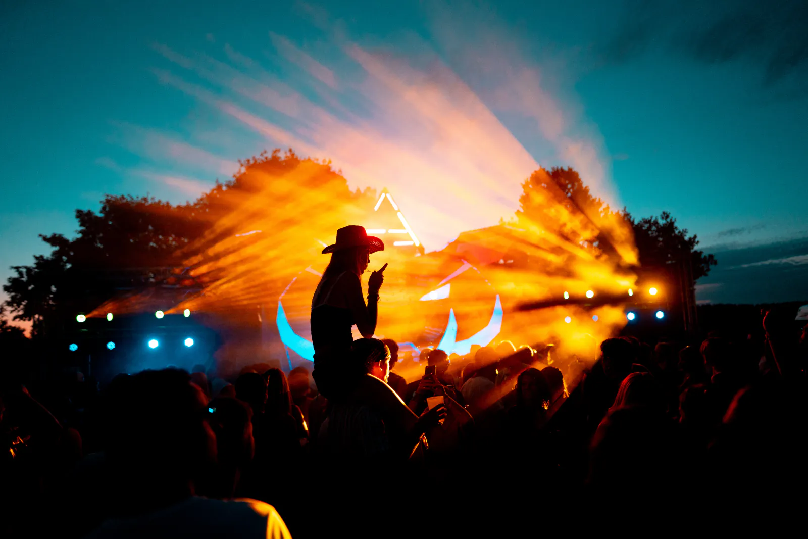 Silhouette mit Cowboyhut vor der Lichtshow beim Zauberwald Festival 2026