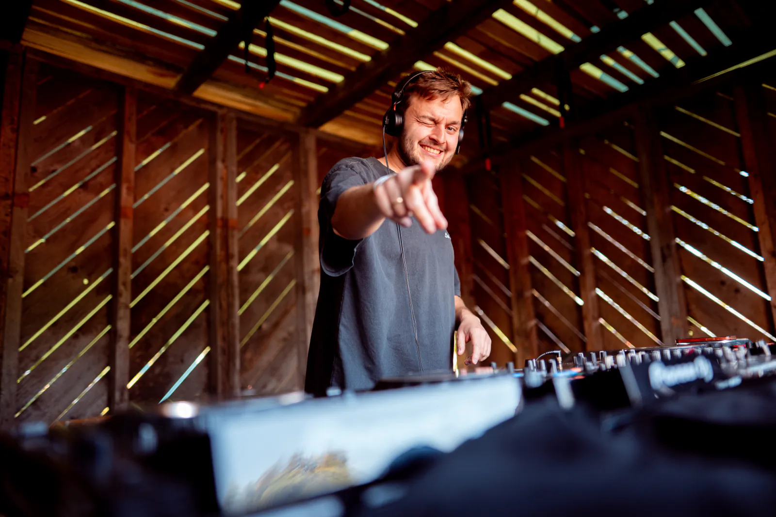 DJ im hölzernen DJ-Pult zeigt ins Publikum