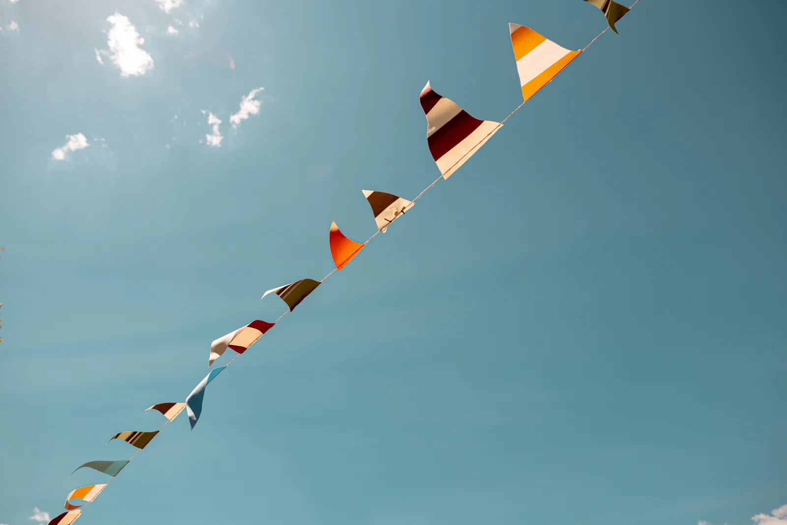 Bunte Wimpelkette vor blauem Himmel über dem Festivalgelände