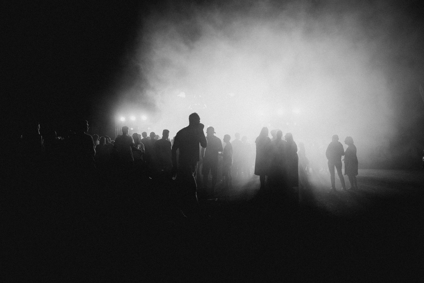 Festivalbesucher in Nebelwolken bei Nacht beim Zauberwald Festival 2025 in Schwarz-Weiss