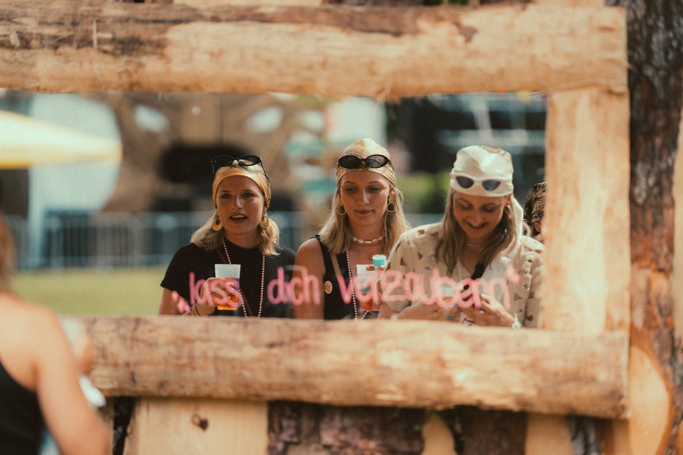 Festivalbesucherinnen durch Holzrahmen mit Schriftzug Lass dich verzaubern beim Zauberwald 2025